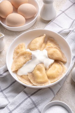 Fresh boiled dumplings in a light plate on a light background. Pattern, background. Homemade craft production, national traditions, Ukrainian cuisine. Close-up, background