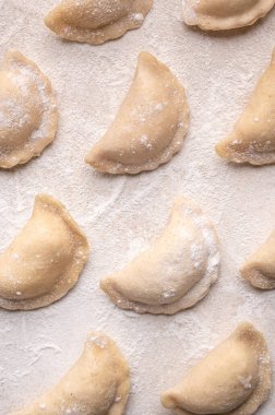 Fresh dumplings in flour on a light background. Pattern, background. Homemade craft production, national traditions, Ukrainian cuisine