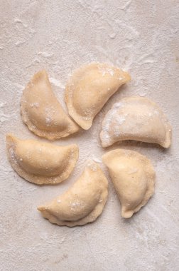 Fresh dumplings in flour on a light background.Background. Homemade craft production, national traditions, Ukrainian cuisine