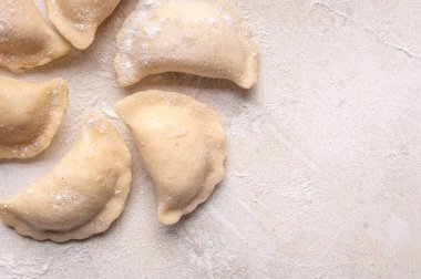 Fresh dumplings in flour on a light background.Background. Homemade craft production, national traditions, Ukrainian cuisine