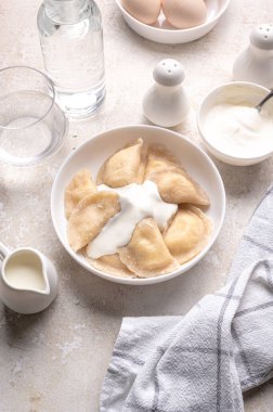 Fresh boiled dumplings in a light plate on a light background. Pattern, background. Homemade craft production, national traditions, Ukrainian cuisine