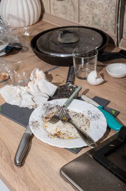 Lavaboda ve tezgahta kirli tabaklar yığılmış dağınık bir mutfak. İskandinav tarzında beyaz cepheli modern mutfak.