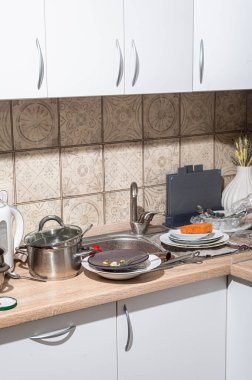 Lavaboda ve tezgahta kirli tabaklar yığılmış dağınık bir mutfak. İskandinav tarzında beyaz cepheli modern mutfak.