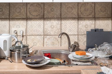 Lavaboda ve tezgahta kirli tabaklar yığılmış dağınık bir mutfak. İskandinav tarzında beyaz cepheli modern mutfak.