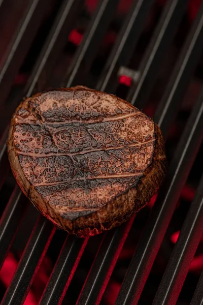 炎の上に鋳鉄グリルで焼くジューシーなステーキ ステーキは完全に調理され グリルマークを持っています 背景は暗く煙が多い — ストック写真