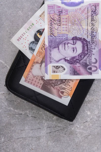 stock image Black wallet on a gray background with 10 and 20 pound notes. Currency of Great Britain (England) with a portrait of Queen Elizabeth