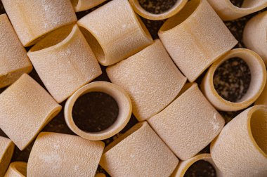 Kapatın. Makarna ve yumurta, taze pişmiş. Buğdaydan ev yapımı makarna. Kahverengi arka planda el yapımı makarna bu fotoğrafın konusu. Erişteler çeşitli şekil ve boyutlarda.. 