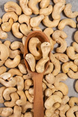 Gri mermer arka planda tahta kaşıkta kaju fıstığı. Bu resim sağlıklı bir atıştırma seçeneğini temsil ediyor ve beslenme, vejetaryenlik, doğal gıda ve sağlık gibi kavramları iletmek için kullanılabilir..