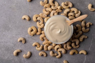 Cashew nut cream cheese in a white bowl, plate on a gray marble stone background. This image represents a healthy snack option and can be used to convey concepts like nutrition, veganism, natural food, and wellness. clipart