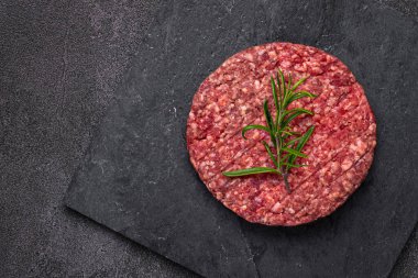 Karanlık bir zemine karşı sulu çiğ hamburger köftesi. Yaradılış, hamburgerciler için mükemmel otantik ve lezzetli bir deneyim için.