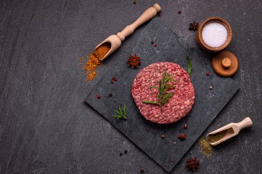 Karanlık bir zemine karşı sulu çiğ hamburger köftesi. Yaradılış, hamburgerciler için mükemmel otantik ve lezzetli bir deneyim için.