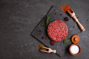 Karanlık bir zemine karşı sulu çiğ hamburger köftesi. Yaradılış, hamburgerciler için mükemmel otantik ve lezzetli bir deneyim için.