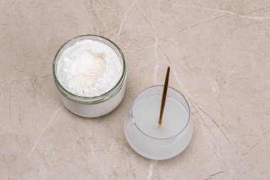 Bir bardak su ve bir kavanoz kolajen Goodnesson mermer bej arka plan. Ev güzelliği prosedürleri. Parlayan cilt ve canlı sağlık için bu güçlü iksirle güzellik rutininizi geliştirin.