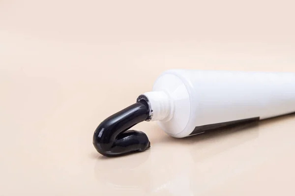 Witte Buis Met Zwarte Tandpasta Een Beige Ondergrond Minimalisme Tandheelkundige — Stockfoto