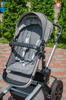 Bahçedeki modern gri bebek arabası. Emniyet kemerleri, bağlayıcılar.