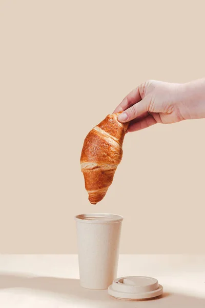 Fresh delicious croissants with an eco cup on a light background. Environmental friendliness, secondary use