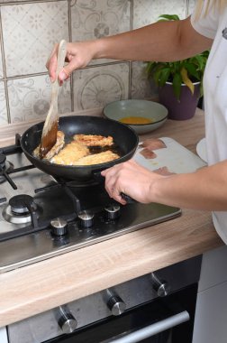 Women's hands fry pieces of fish in a batter - flour and eggs. Home cooking, simple light dishes