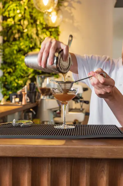 Barın arkasındaki barmen espresso martini yapıyor. Vermut ve kahve ile kokteyl.