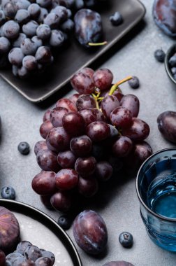 Taze koyu üzüm, incir, yaban mersini ve eriklerin kır taşından yapılmış arka plan manzarası. Mevsimlik meyveler, sonbahar yemek fotoğrafçılığı, sağlıklı beslenme kavramları ve organik ürün tanıtımı için mükemmel.