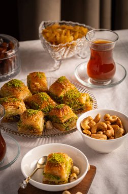 İnce fıstıklarla kaplı pullu baklava. Pekmeze batırılmış fillo hamurunun zengin dokusu ve canlı yeşil fındıklar bu ikonik Orta Doğu tatlısının hoşgörülü doğasını vurguluyor.