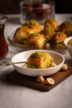 İnce fıstıklarla kaplı pullu baklava. Pekmeze batırılmış fillo hamurunun zengin dokusu ve canlı yeşil fındıklar bu ikonik Orta Doğu tatlısının hoşgörülü doğasını vurguluyor.