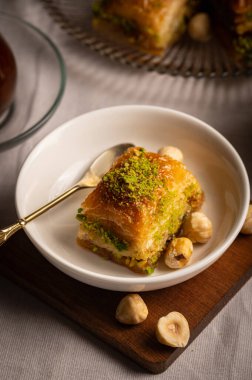 İnce fıstıklarla kaplı pullu baklava. Pekmeze batırılmış fillo hamurunun zengin dokusu ve canlı yeşil fındıklar bu ikonik Orta Doğu tatlısının hoşgörülü doğasını vurguluyor.