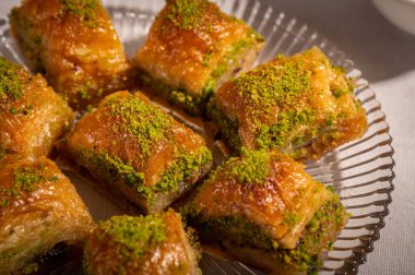 İnce fıstıklarla kaplı pullu baklava. Pekmeze batırılmış fillo hamurunun zengin dokusu ve canlı yeşil fındıklar bu ikonik Orta Doğu tatlısının hoşgörülü doğasını vurguluyor.