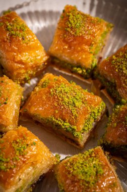 İnce fıstıklarla kaplı pullu baklava. Pekmeze batırılmış fillo hamurunun zengin dokusu ve canlı yeşil fındıklar bu ikonik Orta Doğu tatlısının hoşgörülü doğasını vurguluyor.
