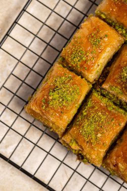 İnce fıstıklarla kaplı pullu baklava. Pekmeze batırılmış fillo hamurunun zengin dokusu ve canlı yeşil fındıklar bu ikonik Orta Doğu tatlısının hoşgörülü doğasını vurguluyor.