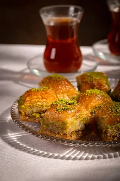 Bir bardak Türk siyah çayının yakınında, içi doğu tatlısı, kurutulmuş meyve ve fındık dolu hurma meyveleriyle servis edilir. Masa örtüsü üzerindeki zarif kompozisyon, Ramazan ayını resmetmek için mükemmel.