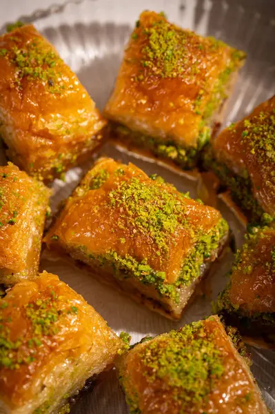 İnce fıstıklarla kaplı pullu baklava. Pekmeze batırılmış fillo hamurunun zengin dokusu ve canlı yeşil fındıklar bu ikonik Orta Doğu tatlısının hoşgörülü doğasını vurguluyor.