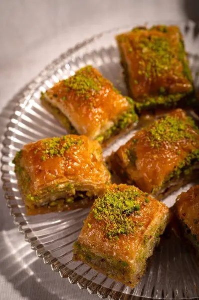 İnce fıstıklarla kaplı pullu baklava. Pekmeze batırılmış fillo hamurunun zengin dokusu ve canlı yeşil fındıklar bu ikonik Orta Doğu tatlısının hoşgörülü doğasını vurguluyor.