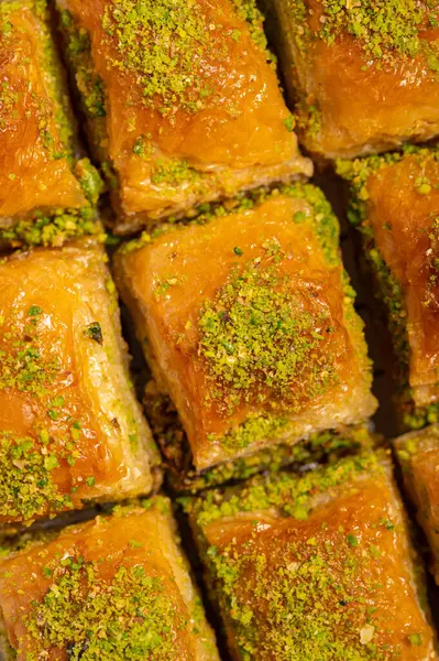 İnce fıstıklarla kaplı pullu baklava. Pekmeze batırılmış fillo hamurunun zengin dokusu ve canlı yeşil fındıklar bu ikonik Orta Doğu tatlısının hoşgörülü doğasını vurguluyor.