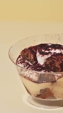 Tarafsız sarı arka planda bir tabakta tiramisu tatlısı.