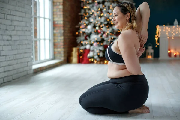 一个穿着运动服的漂亮的胖女人正在身体里锻炼以燃烧脂肪 健身和瑜伽 圣诞节的运动 高质量的照片 — 图库照片