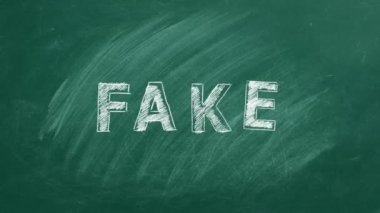 The word FAKE written in chalk on a greenboard. Information and disinformation concept. Fake news.