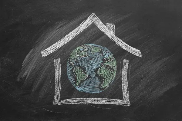 A house is drawn on a blackboard with chalk with a globe inside. Take care of our planet - this is our home. Earth Day. Environment day, save clean planet, ecology concept.