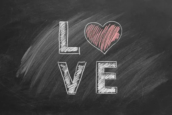 书写爱情的粉笔字母 用心脏代替黑板上的O字 免版税图库图片