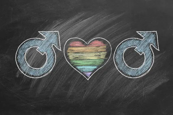男性的性别符号与心形相连 心形为彩虹色 画在黑板上 Lgbt概念 免版税图库图片