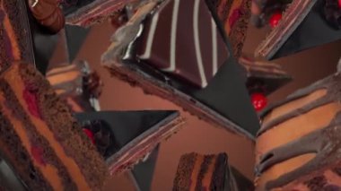 Karamelli katmanlı çikolatalı kek parçaları kahverengi bir arka fona düşer, zengin dokular sergilenir ve kiraz ve çikolata süslemeleri ile zıt renkler sergilenir.