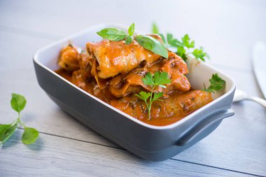 Geleneksel doldurulmuş lahana kıyma ve pilav, ahşap bir masada domates sosu ile servis edilir. .