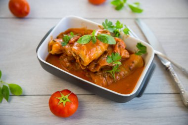 Geleneksel doldurulmuş lahana kıyma ve pilav, ahşap bir masada domates sosu ile servis edilir. .