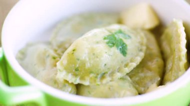 İçi doldurulmuş haşlanmış hamur köfteleri seramik tabakta otlarla dolu..