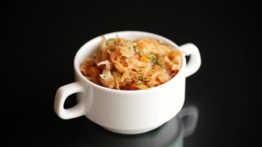 stewed cabbage with carrots and spices in a bowl on a black background.