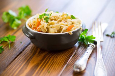 Tahta bir masada seramik bir kasede havuç, soğan ve otlarla haşlanmış lahana..