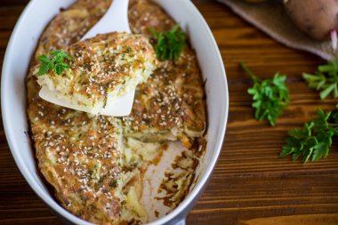 potato casserole with cabbage and spices in a ceramic form on a wooden table.