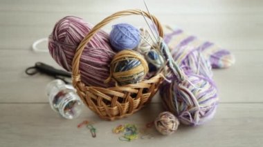 Colored threads, knitting needles and other items for hand knitting, on a light wooden table .