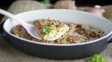 potato casserole with cabbage and spices in a ceramic form on a wooden table.