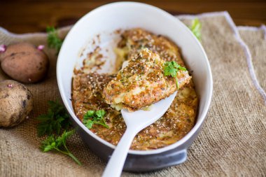 potato casserole with cabbage and spices in a ceramic form on a wooden table.