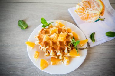 Tahta bir masada portakallı Belçika waffle 'ı pişirdim..